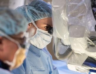 Denver spine surgeon looking through microscope during back surgery.